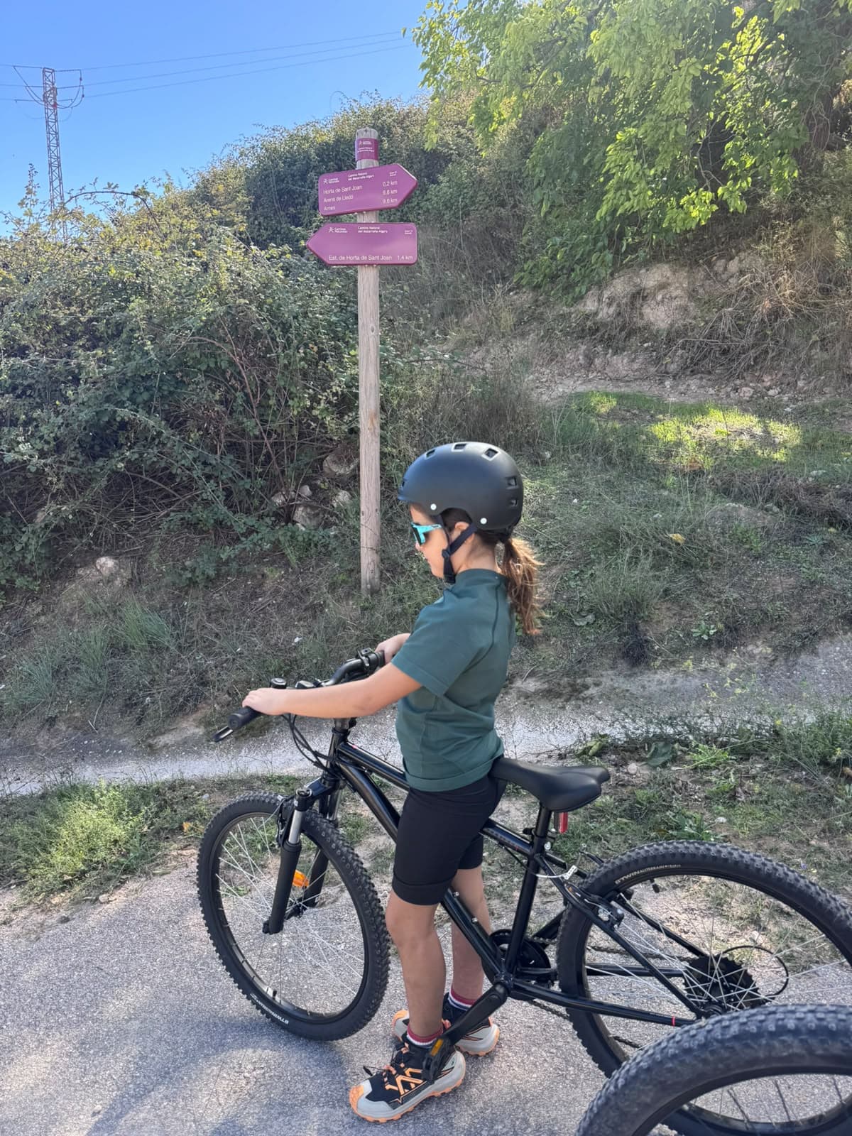 Niña en bici junto a la señal de la Vía Verde de la Terra Alta en Horta de Sant Joan