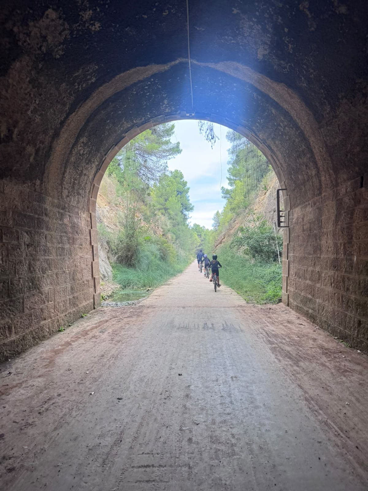 Salida de un túnel de la vía verde con niños en bici